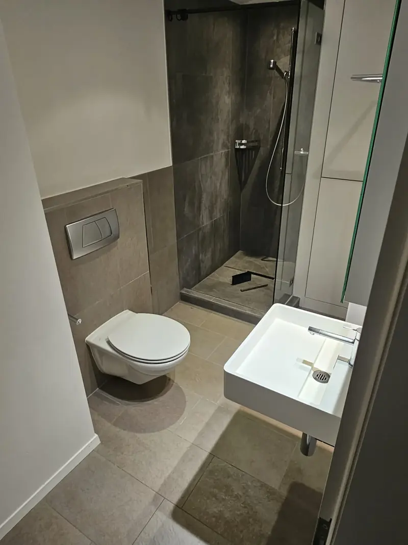 Salle de bain avec douche vitrée, lavabo et WC propres